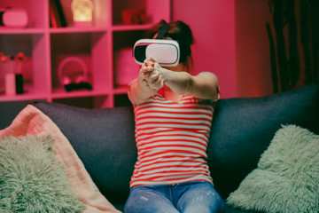 Obraz premium Woman playing and smiling in the VR headset. Virtual reality helmet on color lighting background