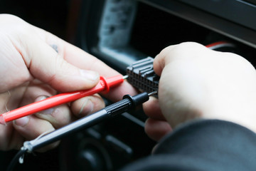 Close up Hand a man use digital multi meter or electric meter check volt of battery with motorcycle service concept