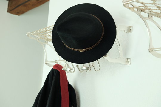 Hut, Mantel und roter Schaal an Gaderobe 