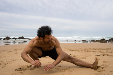 Fototapeta na wymiar A black man stretches his legs on the beach