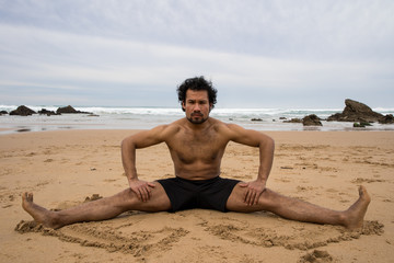 A black man stretches his legs on the beach