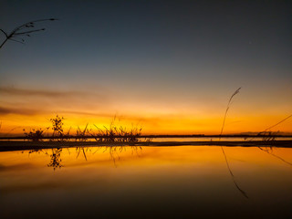 increible reflejo del agua a un atardecer anaranjado en la playa del rio
