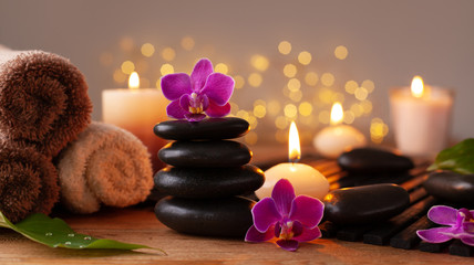 Spa, beauty treatment and wellness background with massage stone, orchid flowers, towels and burning candles.