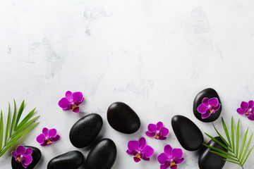 Spa composition with flowers, green leaves and massage stone on white background top view. Beauty treatment and relaxation concept. Flat lay. .