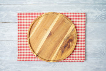Round wooden tray with red checked tablecloth on rustic wooden table Kitchen, cooking or baking mock up background for design.