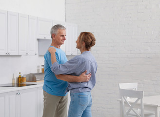 Obraz premium Happy senior couple dancing together in kitchen