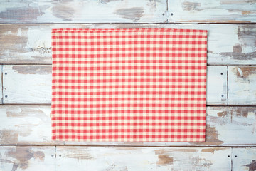 Red checked tablecloth on rustic wooden table. Kitchen, cooking or baking mock up background for design. Top view from above