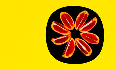 Fresh and juicy grapefruit on the black plate with yellow background