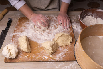 A woman kneads the dough. Plywood cutting board, wooden flour sieve and wooden rolling pin - tools for making dough.