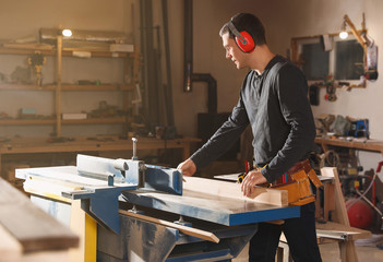 Professional carpenter working with surface planer in workshop - obrazy, fototapety, plakaty