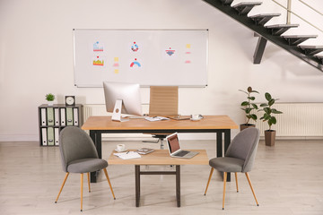 Stylish office interior with large wooden table