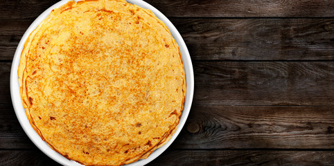 Homemade pancakes on a white plate on a wooden plank