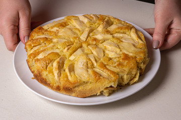 Apple pie, sprinkled with powdered sugar, stands on the table.
