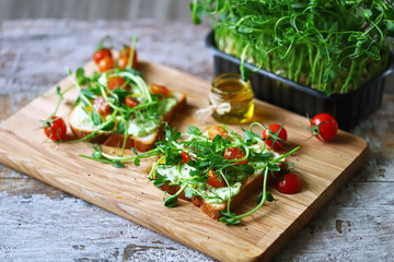 Selective focus. Healthy toasts with avocado pasta, cherry tomatoes and microgreens. Fresh juicy sprouts of peas. Trace elements. Superfoods.