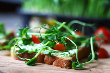 Selective focus. Healthy toasts with avocado pasta, cherry tomatoes and microgreens. Fresh juicy sprouts of peas. Trace elements. Superfoods.
