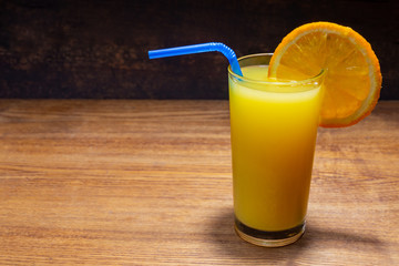 Glass of freshly squeezed orange juice on wooden table