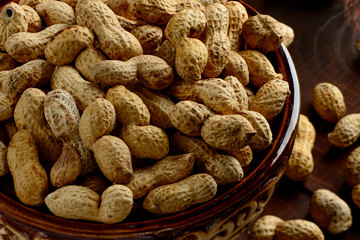 Peanuts in a bowl on the dark background. Peanuts in a shell. Healthy food.
