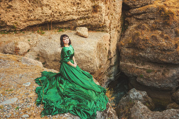 Woman in  lush green dress in Aksu canyon in southern Kazakhstan. Young woman in fairy tale evening...