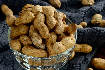 Peanuts in a bowl on the dark background. Peanuts in a shell. Healthy food.