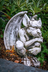 Gardenfigure of a gargoyle sitting in a bed of green plants