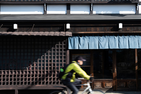 blur of a man ride bicycle ,wooden wall of window and old house in Japan. low key and soft focus.