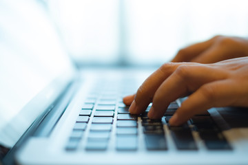 hands typing on a notebook keyboard. selective and soft focus. Subject is blurred