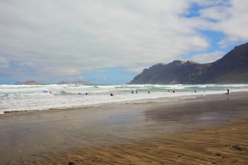 surfers on the Famara Beach on Lanzarote island (Canary Islands)