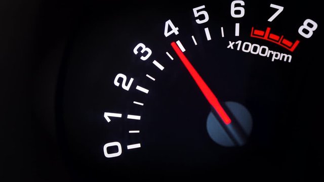 Car tachometer and moving pointer on it indicating the varying engine RPM. Car dashboard. Dashboard details with indication lamps. Car instrument panel