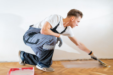 Varnishing of oak parquet floor, mature adult workers using tool