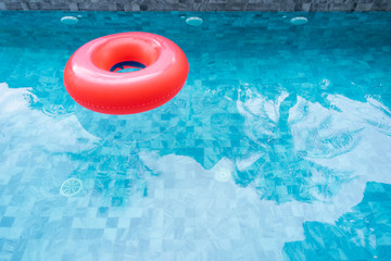 Fototapeta na wymiar Red pool float, ring floating in a refreshing blue swimming pool with shadow of coconut tree. Copy space, summer vacation concept.