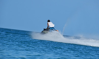 Man riding jet ski scooter over blue sea water