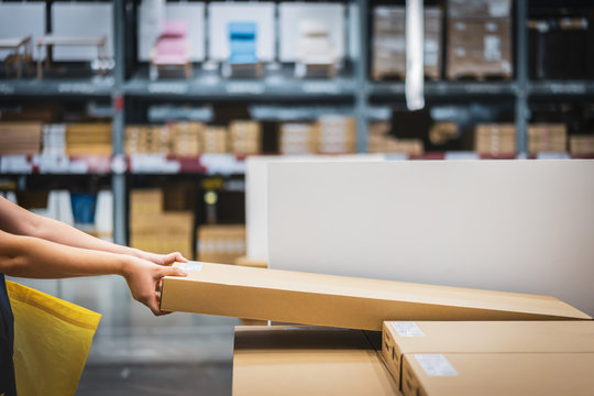 Cardboard box package with blur hand of Asian shopper woman picking product from shelf in warehouse. customer shopping lifestyle in department store or purchasing factory good concepts.