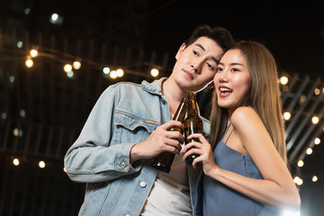 Asian romantic couple dating in pub at night with beer in the bottle valentine day and night party in holiday concepts