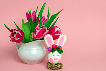 beautiful easter egg and fresh pink tulips on a soft pink background with copy space