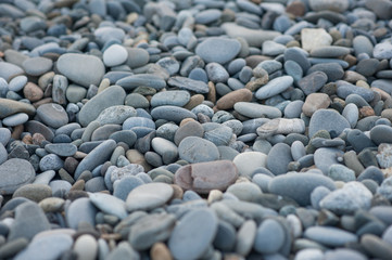 Pebble stones on the shore in sunset light in the background.