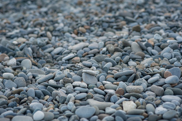 Pebble stones on the shore in sunset light in the background.
