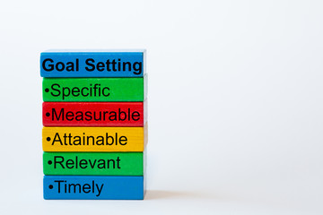 The words: Goal Setting, Specific, Measurable, Attainable, Relevant, Timely are written on colorful blocks