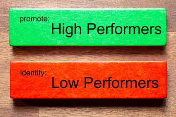 green block with text: promote: High Performers.red block with text: identify: Low Perfomers.The background is a dark wooden table