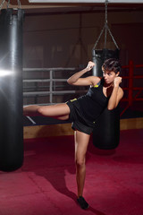 A young Caucasian woman actively trains in the gym and do boxing exercises in boxing gloves in...