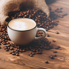 Coffee cup and roasted beans closeup. Morning drink. Hot drink. Wooden background.