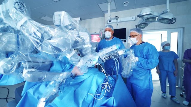 Group of surgeons look at robotic operation. Modern medical equipment in the operating room. Minimally invasive robotic surgery.