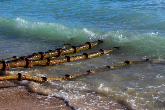Old rusty sewer pipes in a beach. Drainage of waste into the sea.