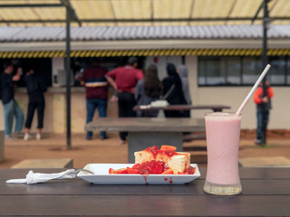 Strawberry smoothie and cheesecake with strawberry jam on a street cafe table.