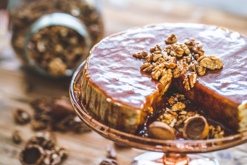 Sweet homemade chessecake with caramel topping and walnut nuts on wooden table. Tasty cake dessert.