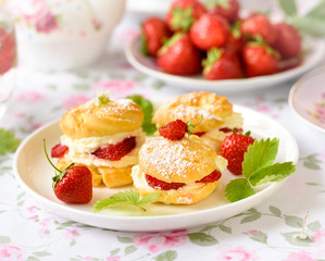 Profiterole or cream puff cakes filled with whipped cream, served with strawberries