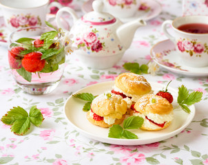 Profiterole or cream puff cakes filled with whipped cream, served with strawberries