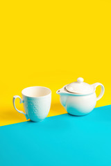 Obraz na płótnie Canvas Tea pot and tea mug on a yellow and blue background