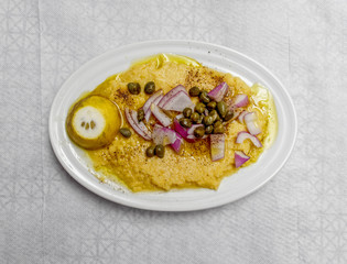 organic "fava" split peas puree Greek gourmet plate with onion, caperi, lemon  and olive olive