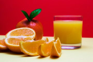 Orange juice with full orange and slices on a colored background