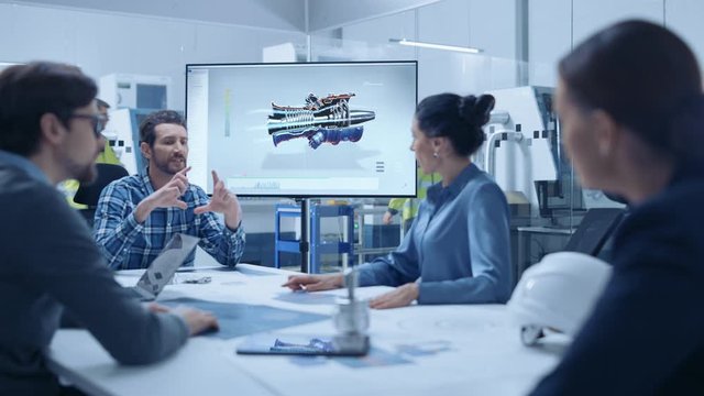 Modern Factory Office Meeting Room: Diverse Team of Engineers, Managers and Investors Talking at Conference Table, Use Interactive TV, Analyze Sustainable Energy Engine Blueprints. High-Tech Facility